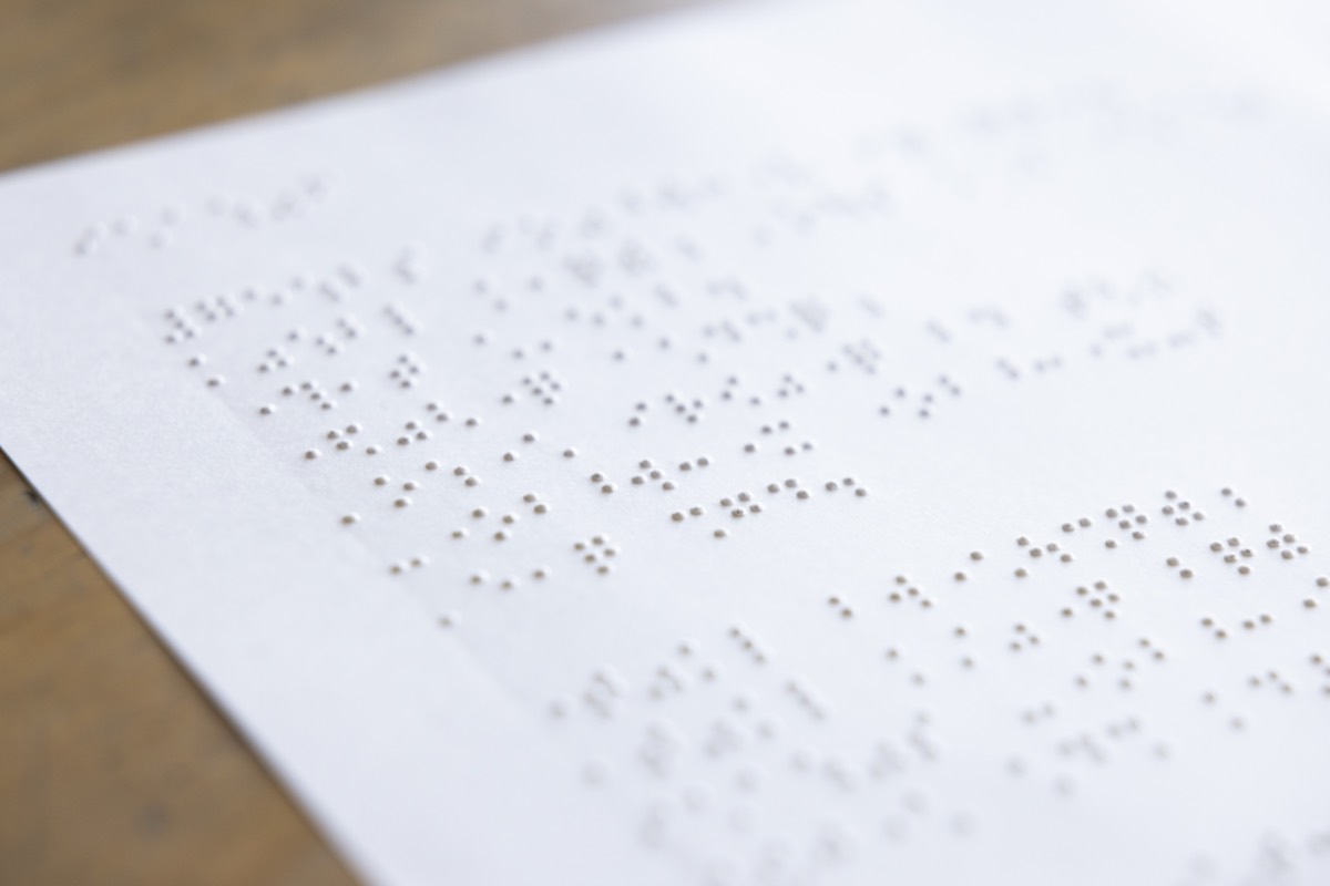 白い紙一面に打たれた点字。浮き上がった点が斜めの光で影をつくっている。